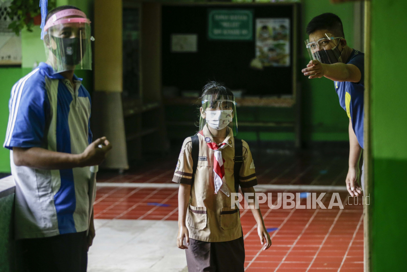  Seorang siswa yang memakai pelindung wajah mengikuti instruksi dari seorang guru saat mengikuti uji coba pembukaan kembali sekolah di Jakarta, Indonesia, 07 April 2021. 