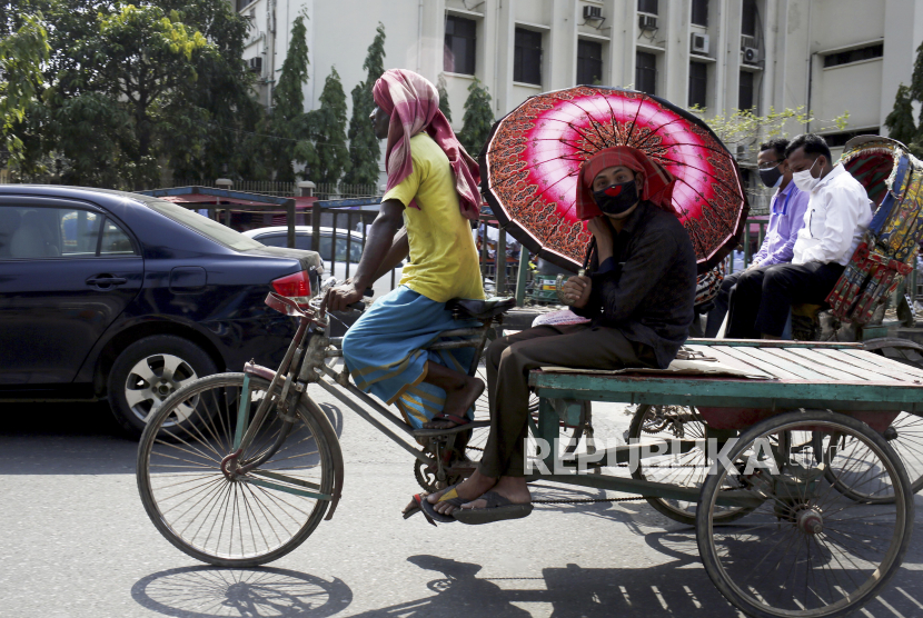 Seorang warga menggunakan payung saat menaiki becak ketika terjadi gelombang panas di Dhaka, Bangladesh, Selasa (27/4). Gelombang panas yang terjadi di Bangladesh itu merupakan yang terparah semenjak tujuh tahun terakhir dengan suhu tertinggi mencapai 41,2 derajat celcius dan diperkirakan akan berlangsung hingga 30 April 2021.  EPA-EFE/MONIRUL ALAM