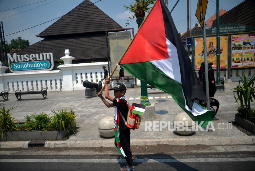 Anak-anak membawa bendera Palestina.