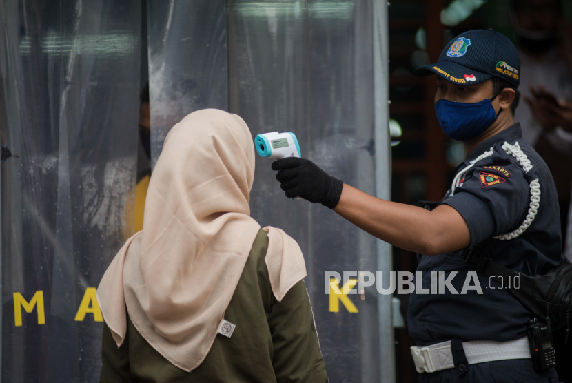 Petugas mengecek suhu tubuh pengunjung pasar saat akan berbelanja di Pasar Perumnas Klender, Jakarta, Senin (15/6). Satpol PP DKI Jakarta mengawasi penerapan protokol kesehatan di pasar tradisional.