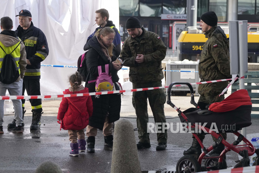 Prajurit Polandia membantu pengungsi Ukraina di stasiun kereta pusat di Warsawa, Polandia.