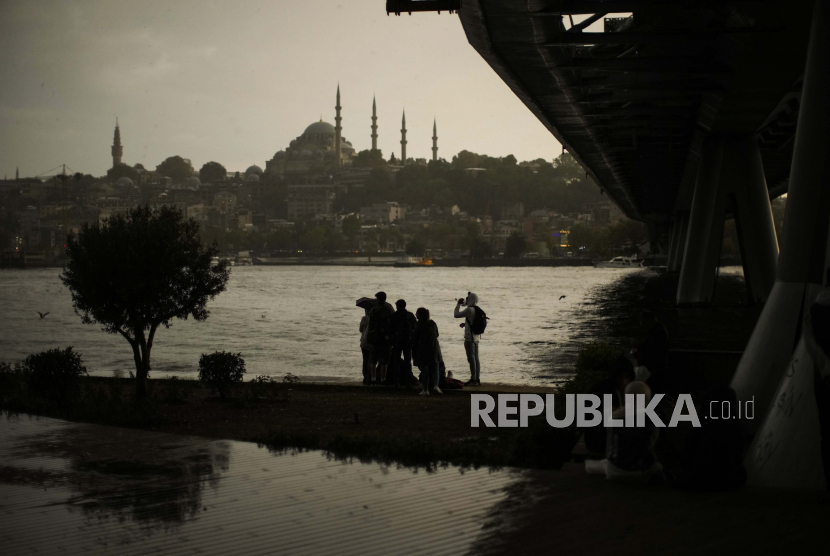 Orang-orang muda berlindung di bawah jembatan melawan hujan pada malam hujan di Istanbul, Turki, Kamis, 22 September 2022.
