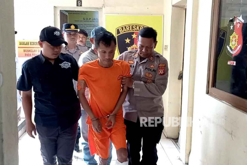 Polisi menggiring tersangka kasus pemerasan dan membawa senjata tajam tanpa hak dan pengerusakan, preman berinisial AK (36 tahun) di Polsek Bandung Kulon, Selasa (4/7/2023). Petugas menembak kaki bagian kiri karena tersangka sempat melakukan perlawana. 