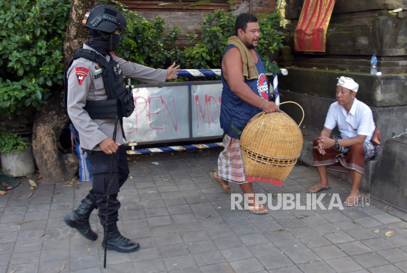 Anggota Brimob Polda Bali membubarkan warga yang menggelar sabung ayam di Denpasar, Bali, Selasa (24/3/2020). Polisi menertibkan warga yang berkerumun tersebut untuk pencegahan penyebaran COVID-19
