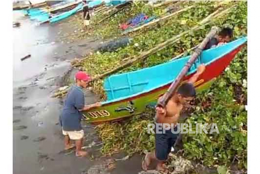 Nelayan mengevakuasi sisa badan perahu yang karam akibat dampak gelombang tinggi yang menerjang Pelabuhan Pamayang, Kabupaten Tasikmalaya, Jawa Barat, Kamis (6/7/2023).