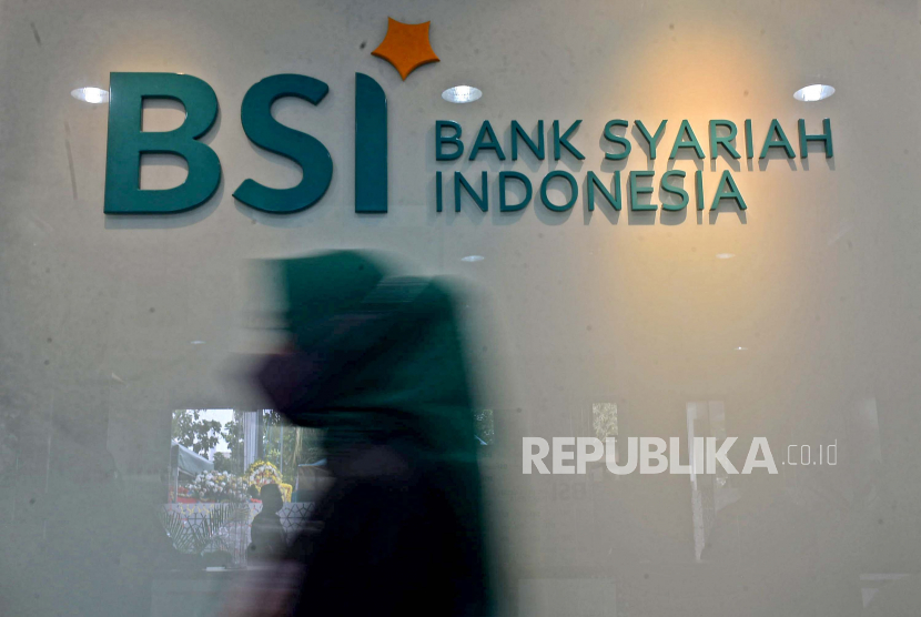 Karyawan melintas di dekat logo Bank Syariah Indonesia (BSI) KC Jakarta Barat, Senin (1/2/2023).