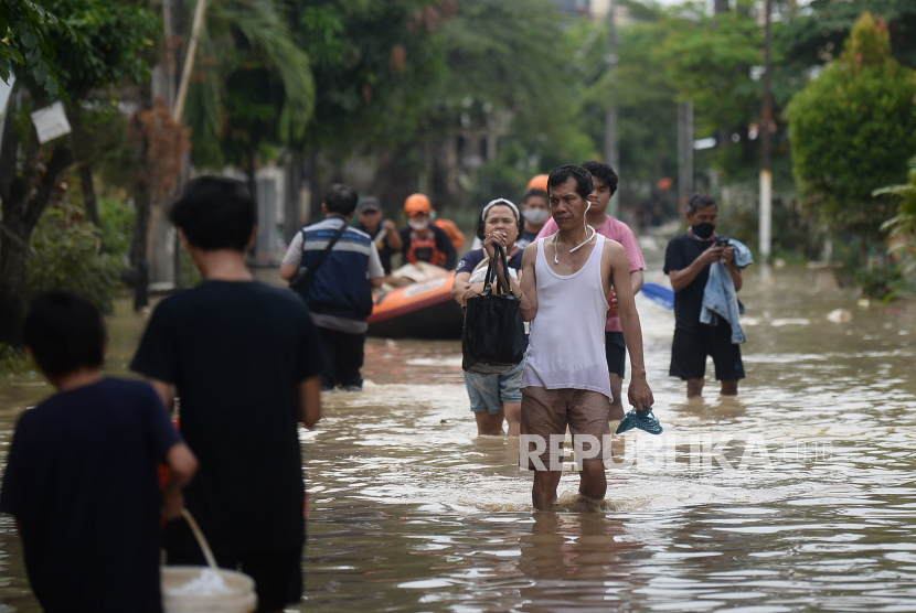 Warga melintasi banjir yang melanda perumahan Villa Jatirasa, Bekasi, Jawa Barat, Ahad (25/10). Banjir akibat luapan kali Cikeas dengan ketinggian 60 cm - 2 meter memasuki pemukiman warga pada (24/10) pukul 23.00 WIB. Prayogi/Republika