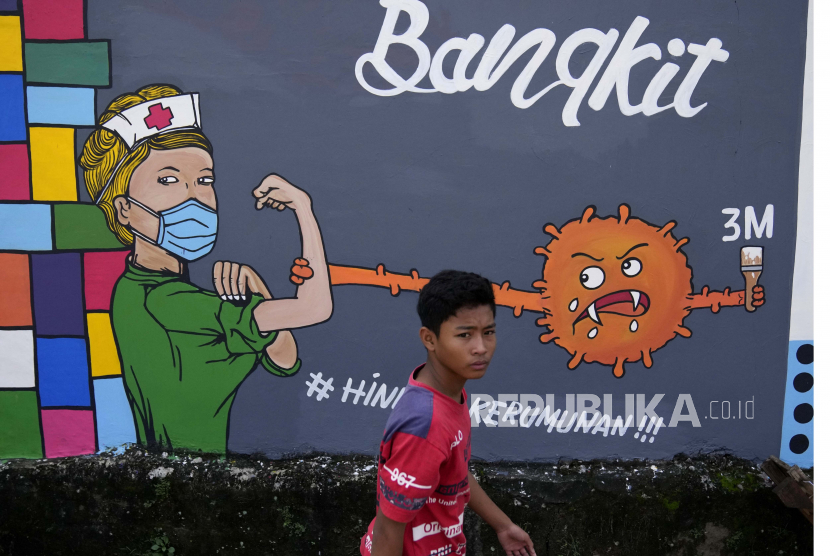 Seorang pemuda berjalan melewati mural bertema coronavirus untuk menghormati pekerja medis di Depok di pinggiran Jakarta, Indonesia, Jumat, 25 Juni 2021. 