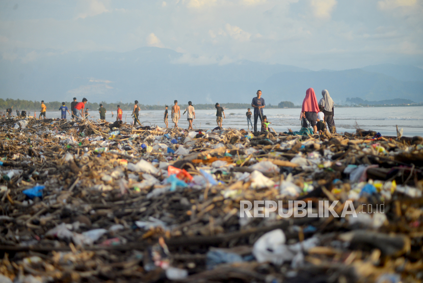 Pengunjung melewati sampah yang memenuhi tepi Pantai Pasir Jambak, Padang, Sumatera Barat, Ahad (29/1/2023). Objek wisata paling utara kota Padang tersebut dipenuhi sampah kayu dan plastik dan menimbulkan bau tidak sedap. 