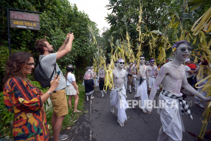 Wisatawan menyaksikan warga yang berhias warna-warni berjalan berkeliling desa dengan membawa berbagai sarana upacara saat tradisi Ngerebeg di Desa Tegallalang, Gianyar, Bali. BPS Bali mencatat ada lima negara dengan kunjungan wisatawan tertinggi di Bali (ilustrasi)