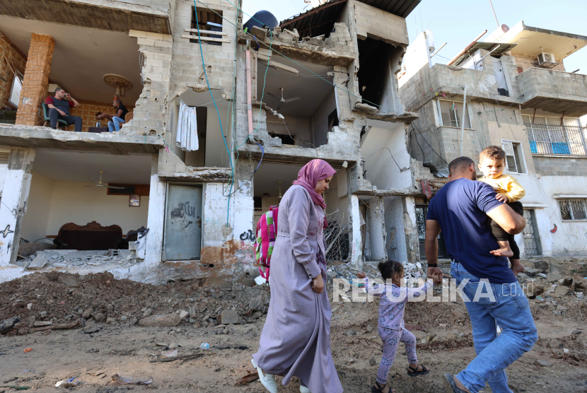 Warga melewati reruntuhan bangunan di Gaza Palestina.