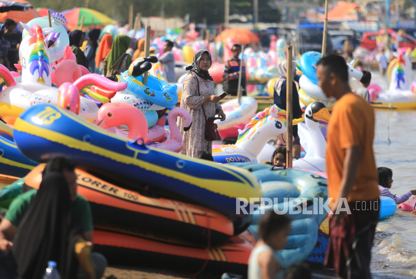 Sejumlah pengunjung menikmati suasana di kawasan wisata Pantai Karangsong, Indramayu, Jawa Barat, Ahad (8/5/2022).  Membludaknya wisatawan di Jabar kurang berdampak pada ekonomi warga  