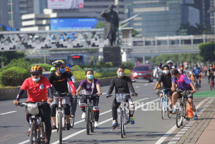 Warga bersepeda  melintasi jalan Sudirman, Jakarta, Ahad (28/3/2021). Pemerintah Provinsi DKI Jakarta memperpanjang masa pemberlakukan pembatasan kegiatan masyarakat (PPKM) mikro hingga 5 April 2021. 