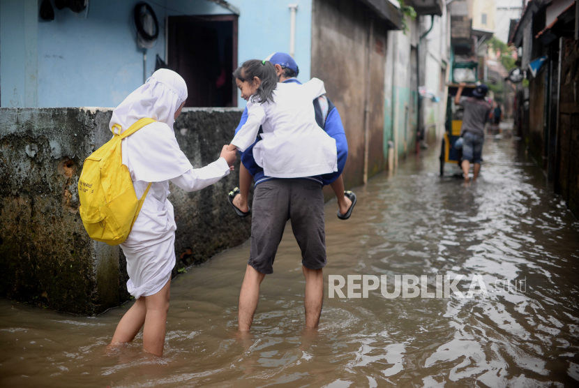 Pelajar berjalan melewati banjir di kawasan Petogogan, Jakarta. Akibat hujan deras yang mengguyur DKI Jakarta, sebanyak 12 RT terendam banjir.