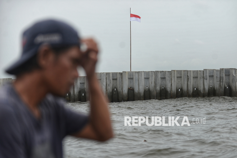Nelayan melintas didekat pagar laut beton yang terpasang di pesisir Cilincing, Jakarta, Kamis (11/9/2025).