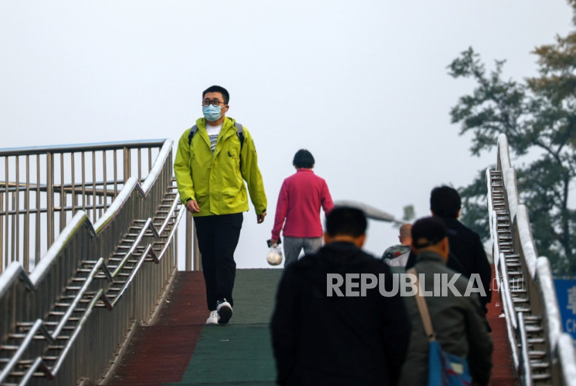 A man wears a face mask as he walks on an overpass in Beijing, China, 30 October 2023. 