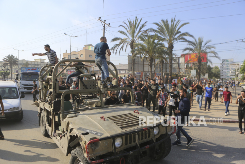 Warga Palestina menaiki kendaraan militer Israel yang diambil dari pangkalan militer yang dikuasai militan Hamas di dekat pagar Jalur Gaza, di Kota Gaza, Sabtu, 7 Oktober 2023.