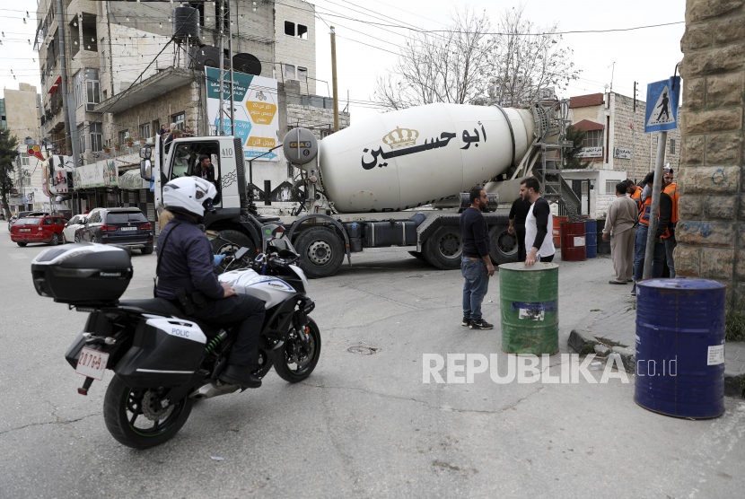 Pekerja Palestina mengisi tong dengan semen yang akan digunakan untuk memblokir jalan. ilustrasi