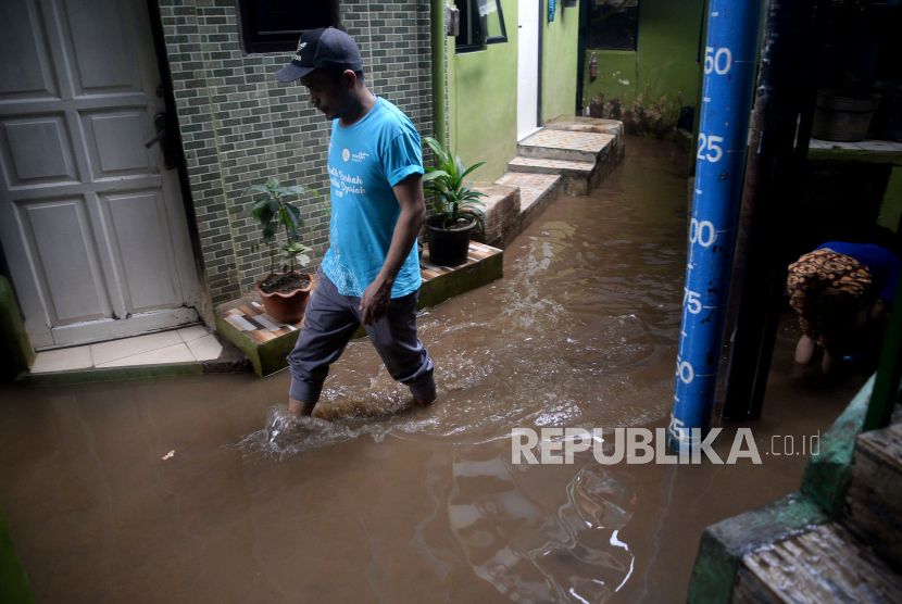 Warga melintasi banjir yang merendam kawasan Kebon Pala, Kampung Melayu, Kecamatan Jatinegara, Jakarta Timur, Senin (8/11/2021). 