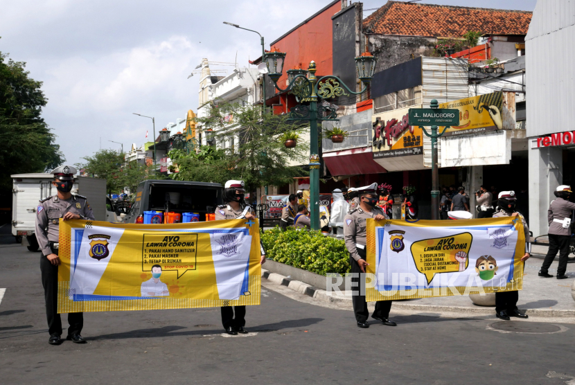 Anggota Kepolisian membawa spanduk saat mengikuti kampanye penggunaan masker oleh Polda DIY di kawasan Malioboro Yogyakarta, Kamis (10/9). Selain kampanye penggunaan masker juga pembagian masker gratis. Hal ini salah satu upaya pengendalian Covid-19 yang akhir-akhir ini kurvanya meningkat.