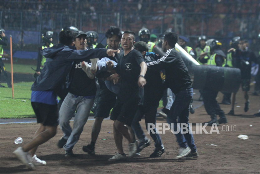 Sejumlah penonton membawa rekannya yang pingsan akibat sesak nafas terkena gas air mata yang ditembakkan aparat keamanan saat kericuhan usai pertandingan sepak bola BRI Liga 1 antara Arema melawan Persebaya di Stadion Kanjuruhan, Malang, Sabtu (1/10/2022). 