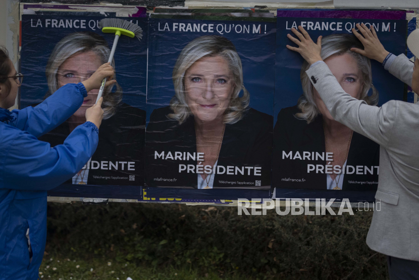 Bastian Maldiney dan Emma Mino menempelkan poster pemilihan calon presiden sayap kanan Prancis Marine Le Pen, Selasa, 29 Maret 2022 di Vigneux-De-Bretagne, Prancis barat.  Capres Sayap Kanan Prancis Ingin Larang Jilbab Secara Total