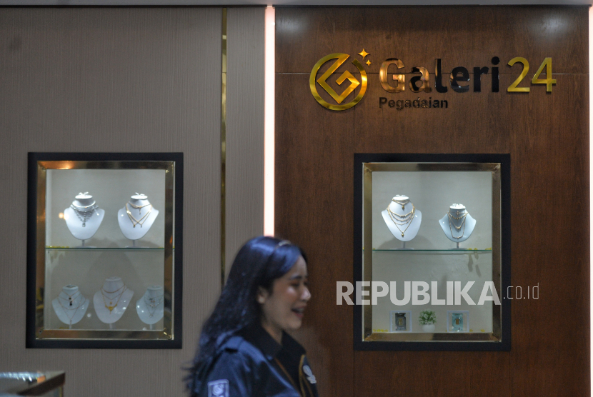 Karyawan melintas di dekat koleksi emas di Galeri24 Pegadaian, Jakarta Selasa (11/1/2022).