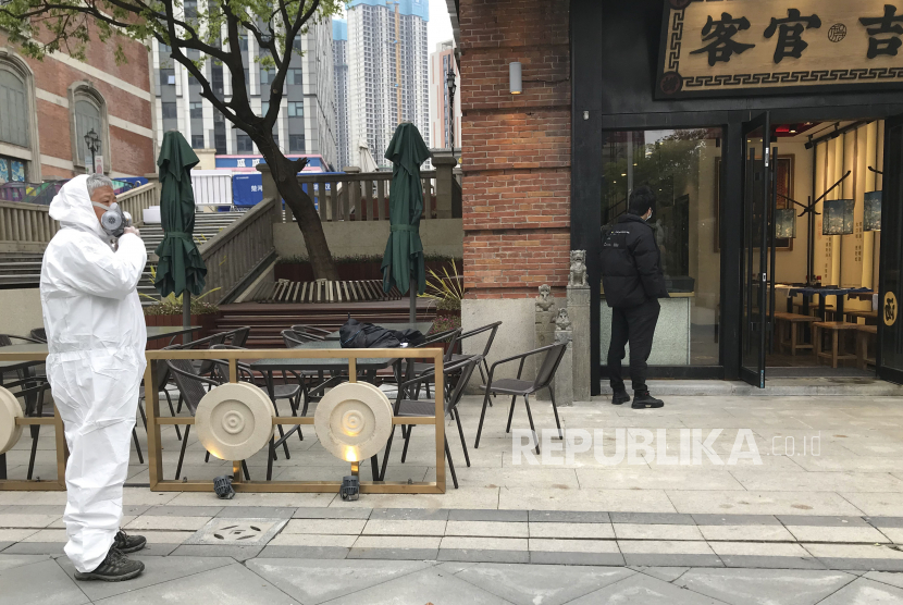 Seorang pekerja toko mengenakan pakaian pelindung menunggu pelanggan di sebuah jalan ritel yang dibuka kembali di Wuhan. Menurut WHO ada 16 negara yang belum melaporkan adanya temuan kasus corona. Ilustrasi.