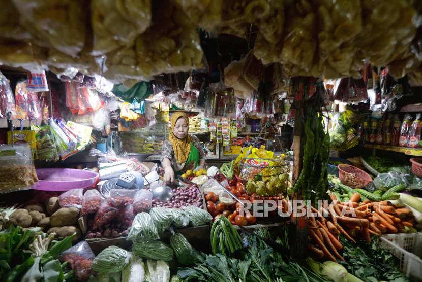 Seorang pedagang sembako menunggu pelanggan di pasar tradisional.