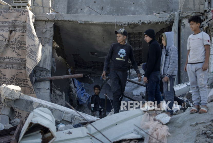 Warga Palestina memeriksa rumah yang hancur akibat serangan udara Israel di timur kota Deir al Balah, Jalur Gaza, 19 Desember 2023.