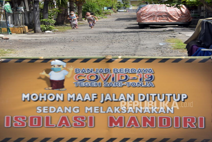 Dua anak bermain di jalan perumahahan yang ditutup karena warganya melakukan isolasi mandiri di Denpasar, Bali, Sabtu (2/5/2020). Penutupan jalan tersebut untuk mencegah keluar masuknya orang dalam upaya mengurangi risiko penularan COVID-19