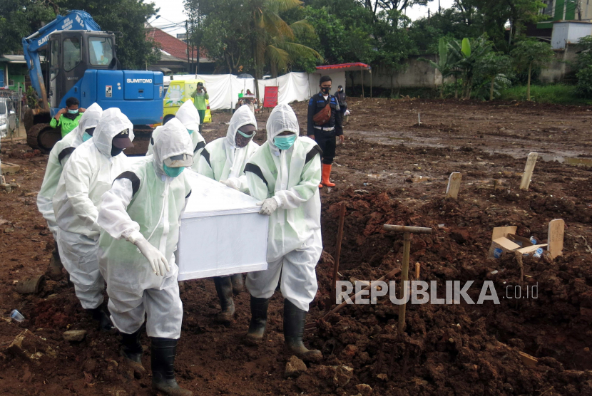 Petugas pemakaman membawa peti jenazah korban COVID-19 di TPU Srengseng Sawah Dua, Jagakarsa, Jakarta Selatan, Selasa, (2/2/2021).