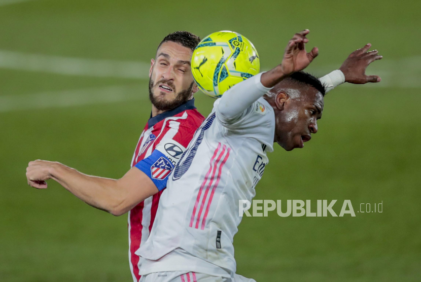 Gelandang Atletico Madrid Koke (kiri) berduel bola dengan winger Real Madrid Vinicius Junior dalam pertandingan derby Madrid di La Liga Spanyol, Ahad (13/12) dini hari WIB.