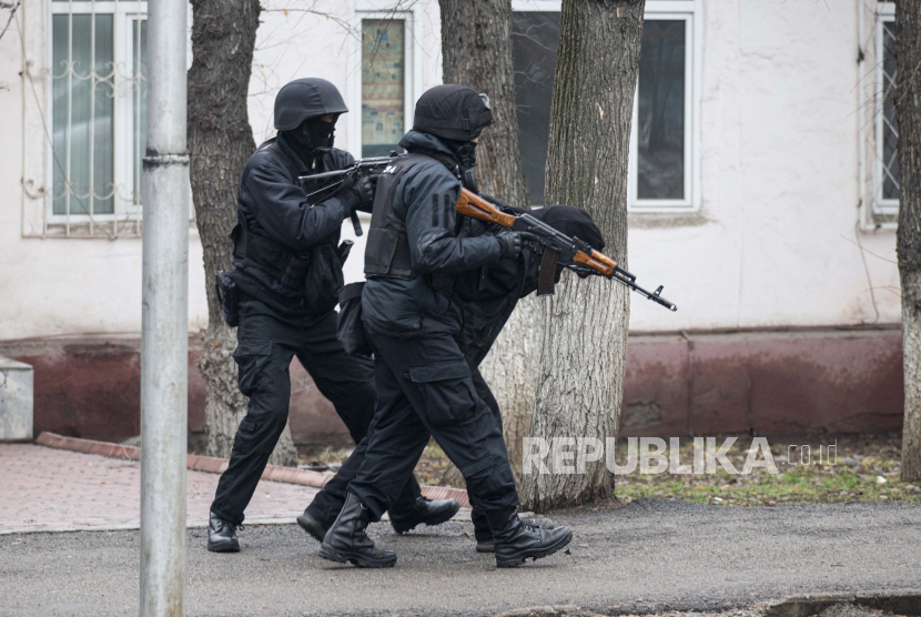 Petugas polisi anti huru hara bersenjata bersiap-siap untuk menembak ketika mereka mengendalikan jalan setelah bentrokan di Almaty, Kazakhstan, Sabtu, 8 Januari 2022. Pasukan keamanan Kazakhstan menahan total 7.939 orang dalam kerusuhan pekan lalu.