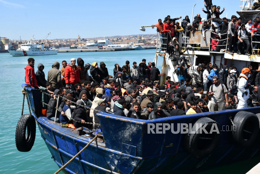  Beberapa dari 600 migran yang diselamatkan dengan kapal pukat sekitar 100 mil dari pantai Sisilia tiba di pelabuhan Catania, Italia, Rabu (12/4/2023). Kapal tersebut dikawal oleh 