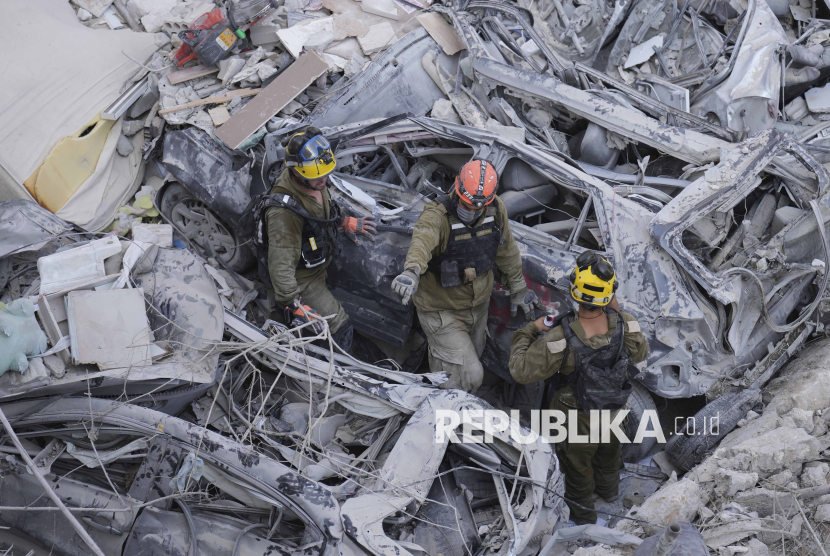Tentara Israel mencari korban selamat di tengah reruntuhan bangunan tempat tinggal yang hancur akibat serangan rudal Iran di kota Bat Yam, Israel tengah, Ahad (15/6/2025).