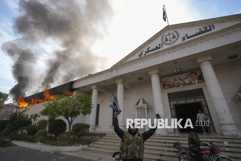 Pejuang oposisi meluapkan kegembiraanya saat membakar bangunan pengadilan militer di Damaskus, Suriah, Ahad (8/12/2024). Kekuasaan Partai Baath di Suriah tumbang pada Ahad (8/12/2024). Hal itu ditandai ibu kota Damaskus lepas dari kendali rezim Presiden Bashar al-Assad. Runtuhnya kekuatan pasukan Assad di ibu kota mengakhiri 61 tahun pemerintahan Partai Baath yang penuh kekerasan dan 53 tahun kekuasaan keluarga Assad.