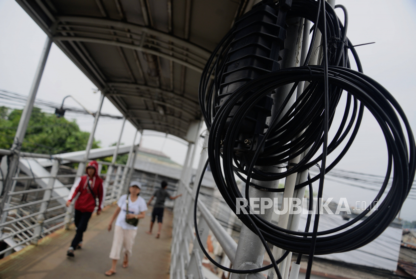 Warga berjalan di dekat instalasi kabel-kabel yang semrawut di kawasan Kramat Jati, Jakarta (ilustrasi) 