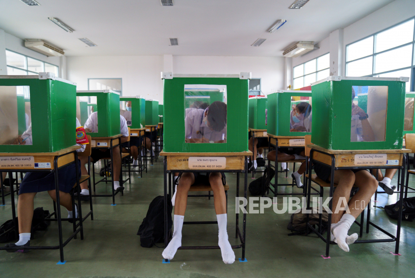 Siswa sekolah Sam Khok mengenakan masker wajah dan pelindung wajah terlihat di dalam kotak suara tua yang dipecah menjadi beberapa partisi saat mereka menghadiri kelas setelah pemerintah Thailand melonggarkan langkah-langkah isolasi dan memperkenalkan jarak sosial untuk mencegah penyebaran penyakit coronavirus (Covid-19), sebagai sekolah yang dibuka kembali secara nasional, di provinsi Pathum Thani, Thailand, 1 Juli 2020. 