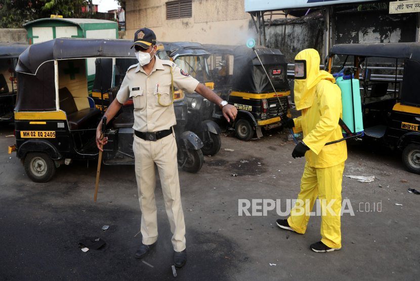 Pekerja sipil menyemprotkan disinfektan ke polisi di Mumbai, India, saat pandemi Covid-19.