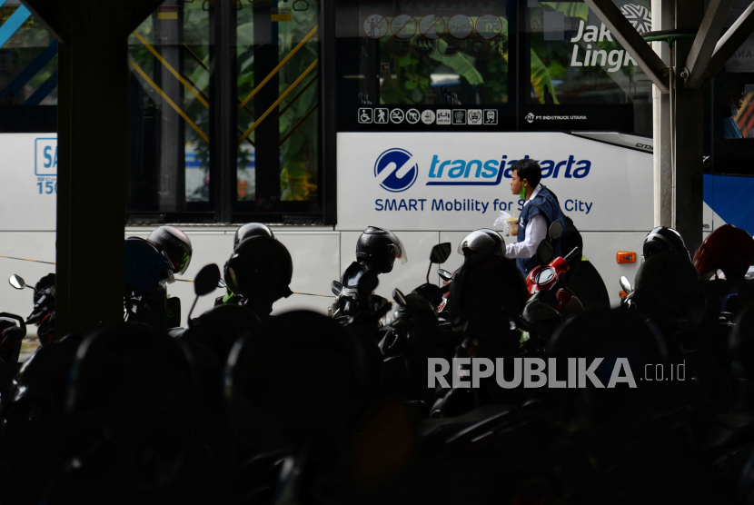 Pengendara berjalan menuju halte Transjakarta usai memarkirkan motor di Park and Ride Vertical Terminal Ragunan, Jakarta Selatan.