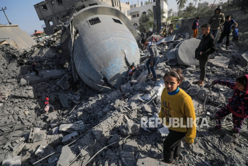 Warga Palestina berjalan di tengah reruntuhan.