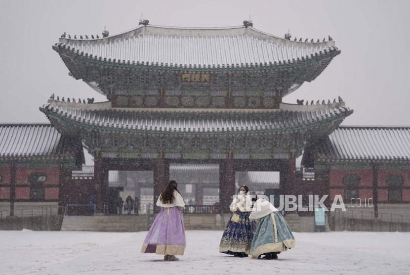 Pengunjung berfoto di salju di Istana Gyeongbok, salah satu landmark terkenal Korea Selatan, di Seoul, Korea Selatan, Rabu, 19 Januari 2022. Istana akan kembali dibuka untuk wisata malam hari mulai bulan depan.