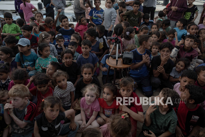 Anak-anak berkumpul di bioskop darurat yang didirikan di antara tenda-tenda kamp pengungsi Rafah, Jalur Gaza bagian selatan, 28 April 2024. 