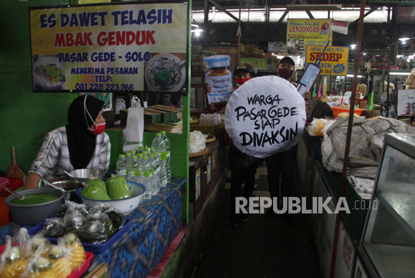 Relawan mengusung poster bertuliskan Warga Pasar Gede Siap Divaksin saat aksi di Pasar Gede Solo, Jawa Tengah, Kamis (14/1/2021). Aksi tersebut sebagai dukungan program vaksinasi COVID-19 untuk memutus rantai penyebaran virus COVID-19. 