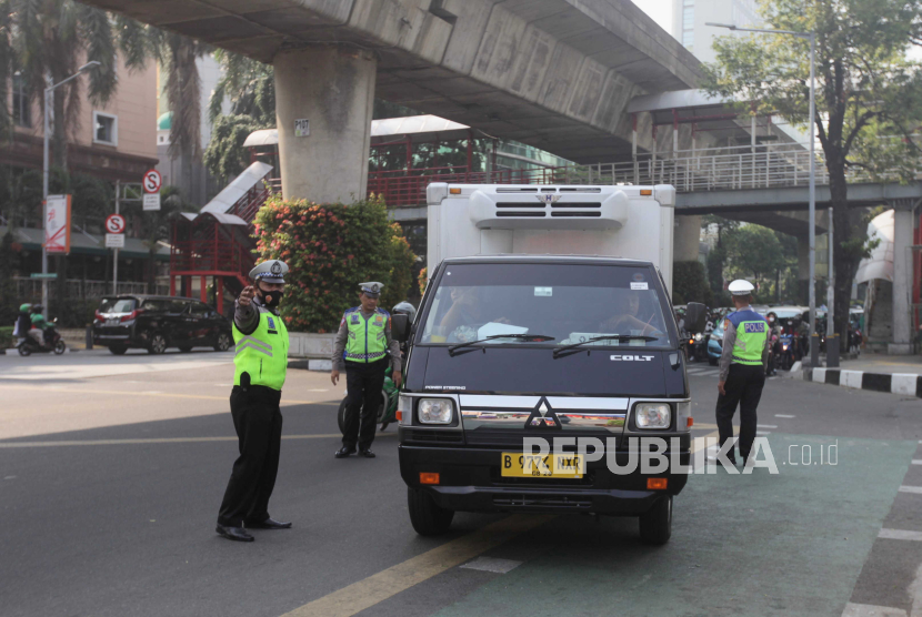 Polisi menghentikan kendaraan saat uji coba tilang uji emisi di Terminal Blok M, Jakarta Selatan, Jumat (25/8/2023).