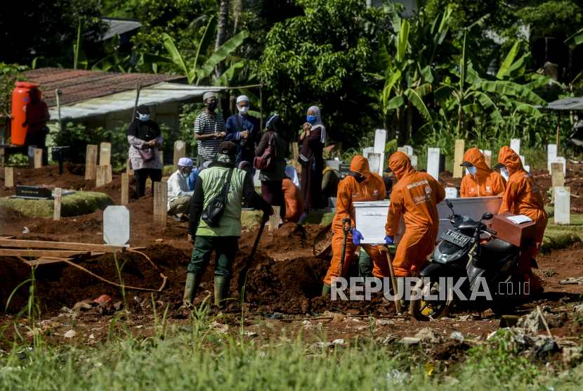 Warga melakukan ziarah kubur saat ada jenazah dimakamkan di area pemakaman korban Covid-19 di TPU Pondok Ranggon, Jakarta, Senin (25/5).