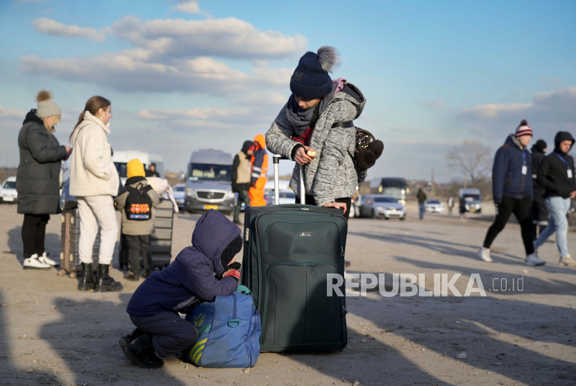 Pengungsi berangkat ke Rumania setelah melarikan diri dari Ukraina, berhenti sejenak saat mereka berjalan di perbatasan di Palanca, Moldova, Kamis, 17 Maret 2022.