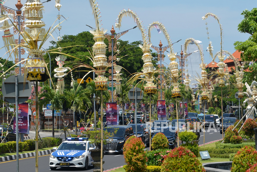 Kendaraan melintas di jalan yang pinggirnya dihiasi penjor atau hiasan janur kuning khas Bali di Jalan Bandara Ngurah Rai, Kabupaten Badung, Bali, Kamis (10/11/2022). Pemerintah memasang penjor, bendera negara peserta, baliho, dan spanduk di sejumlah jalan protokol di Bali untuk memeriahkan KTT G20 yang akan berlangsung pada 15-16 November 2022. 