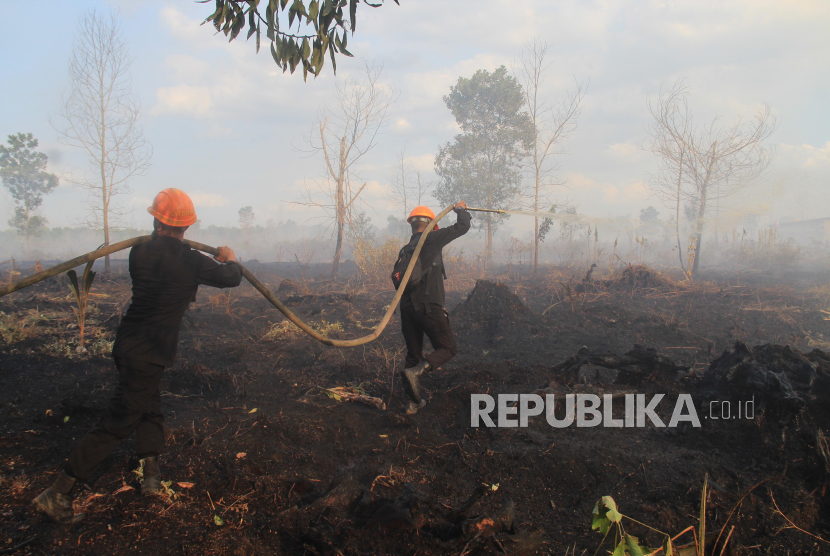 Personel Sat Brimob Polda Kalbar menyemprotkan air ke lahan gambut yang terbakar di Desa Sungai Raya Dalam, Kecamatan Sungai Raya, Kabupaten Kubu Raya, Kalimantan Barat, Jumat (26/7/2024). 